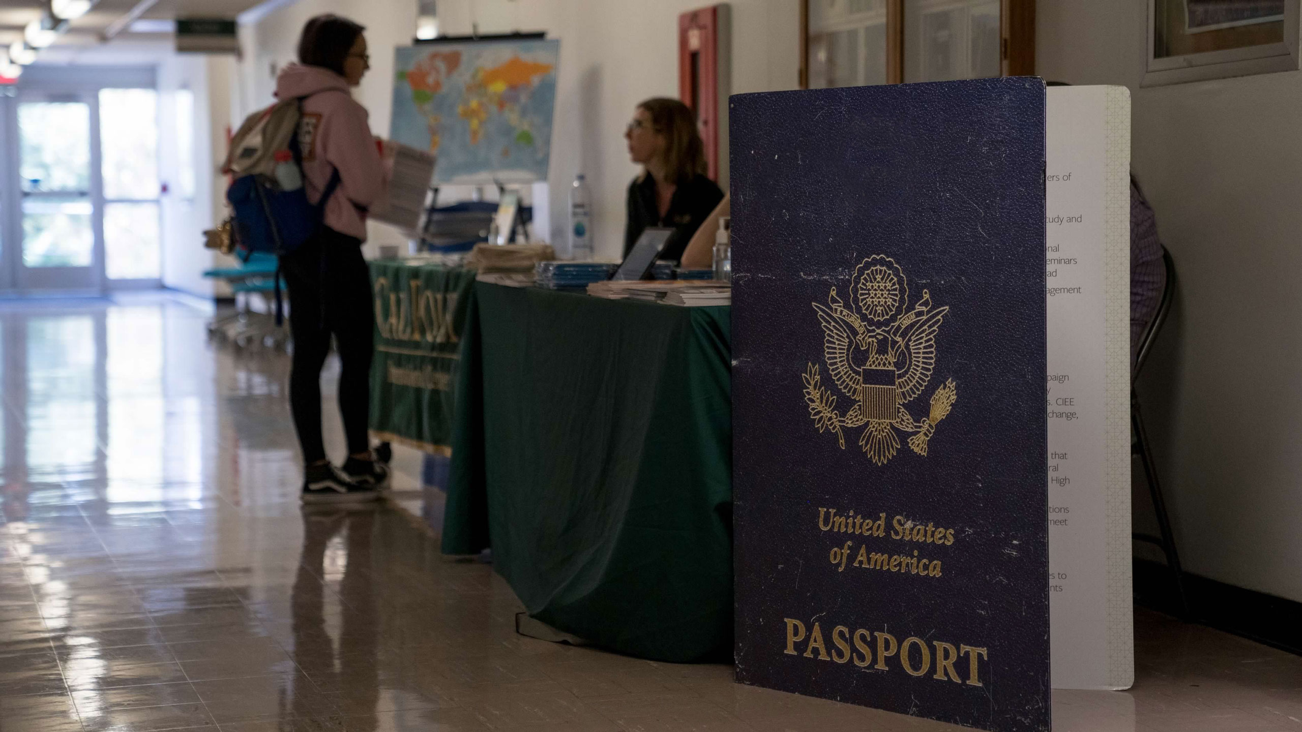 A staff member greets a student outside the passport event in building 52