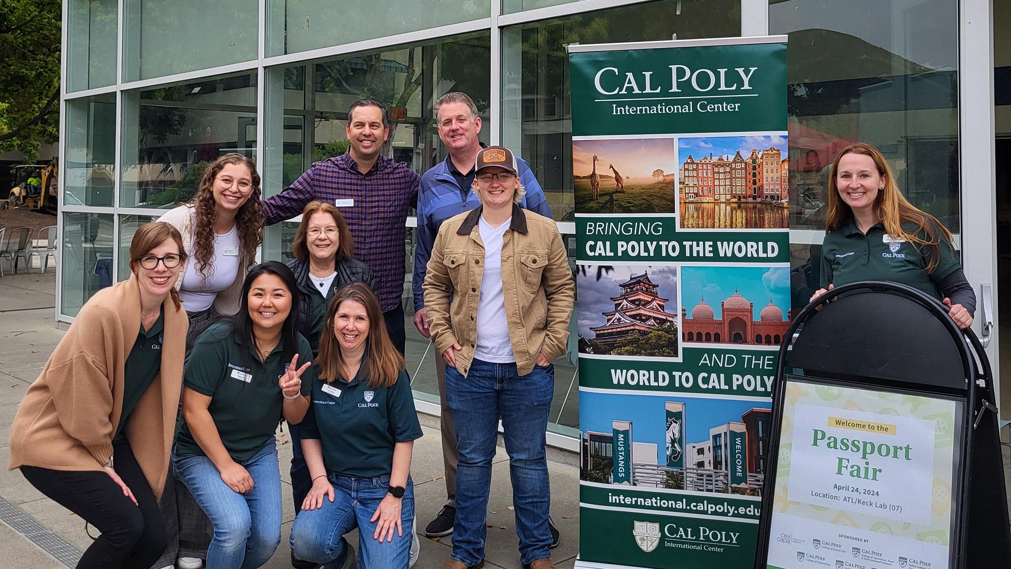 Students posing for a photo next to an advertisement