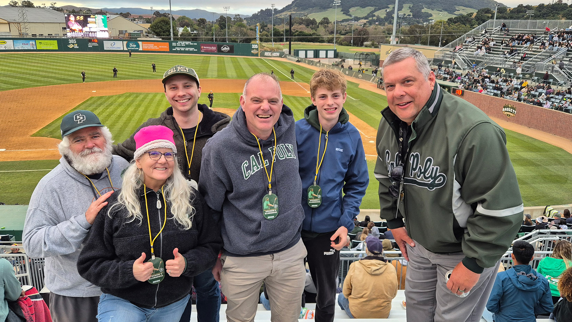 People posing and smiling for a photo at a baseball game