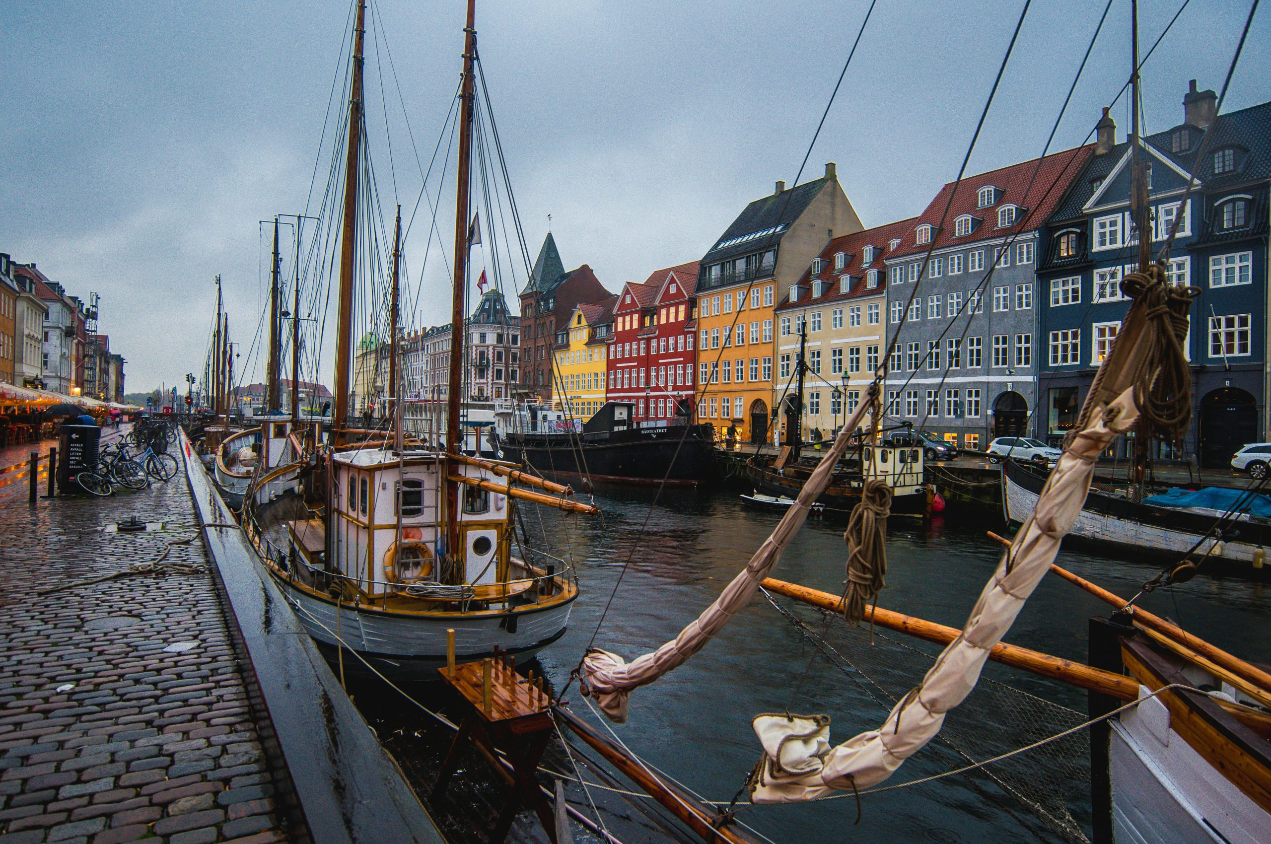 Boats docked along Nyhavn harbor with colorful historic buildings in Copenhagen, Denmark.