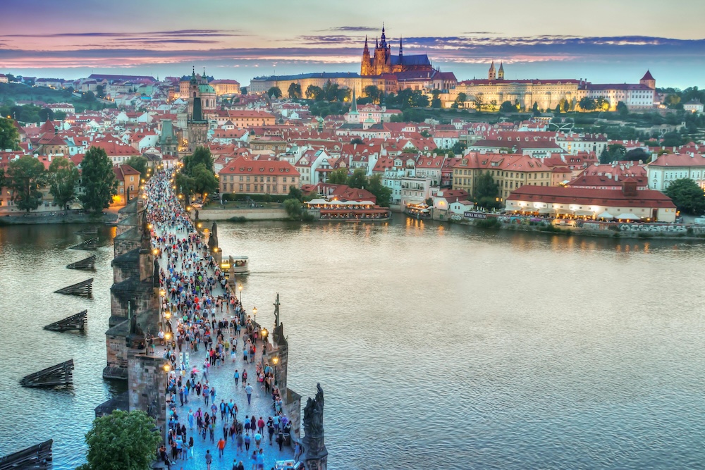 prague-charles-bridge-cityscape Charles Bridge crosses the Vltava River toward Prague’s historic cityscape and Prague Castle at dusk.